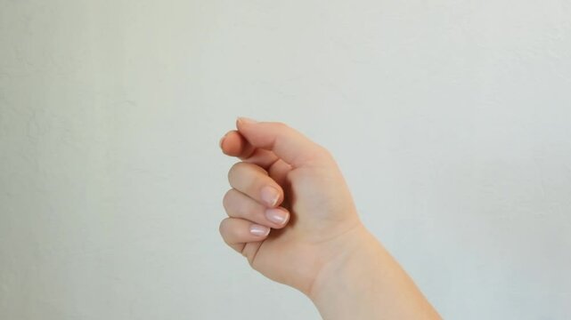 Snapping fingers. A woman's hand snapping her fingers against a white wall. HD video footage