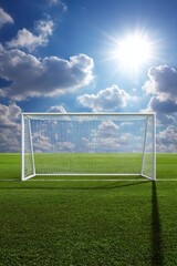 Fototapeta premium Serene soccer field under bright sky featuring a goalpost with net on green grass pitch with clouds and sun creating a peaceful and inviting atmosphere perfect for sports