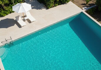 An inviting turquoise pool with white loungers under an umbrella offers a peaceful, luxurious escape.