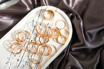 Collection of gold hoop earrings displayed on a silky surface in a bright room