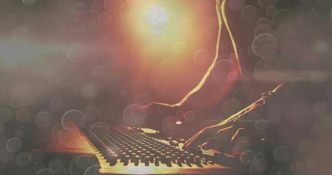 Man playing MIDI controller in dim music studio, laptop glowing with warm backlight flares