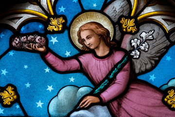 Stained glass (19th century) of an angel in heaven with crown and flowers.