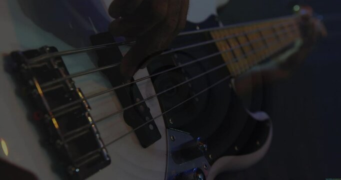 Musician plucking bass guitar strings in dim music studio, displaying animated waveform graphics
