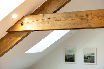 Charpentes en bois apparentes dans une pièce de vie chaleureuse, mêlant authenticité, volume et architecture intérieure de caractère.
