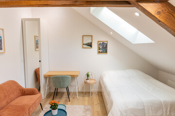 Intérieur lumineux d’une pièce de vie combinant salon et espace nuit avec lit, dans un style moderne et fonctionnel
