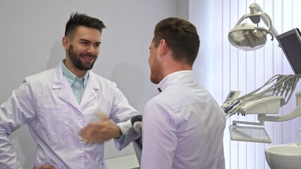 Young dentist warmly welcomes patient at modern clinic