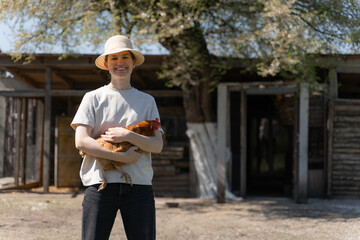 young woman in a straw hat holding a chicken