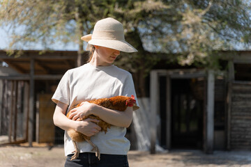 young woman in a straw hat holding a chicken