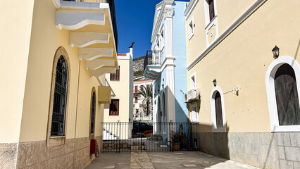 Obraz premium Traditional Mediterranean Alley With Colorful Buildings And Palm Tree In Kastellorizo Island, Greece, On A Sunny Day, Concept Of Historic Architecture, Real Estate, Tourism, Summer Vacation, Cultural 
