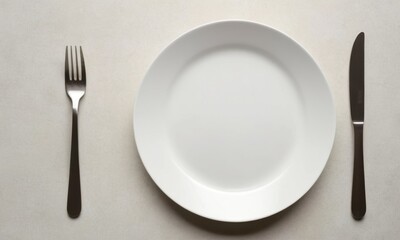 A simple white plate with a fork and knife, perfect for table settings or still life photography