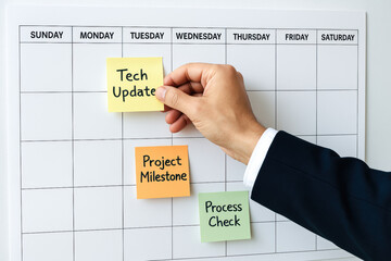 A professional hand positions colorful sticky notes on a calendar to emphasize key business strategies project milestones and essential process checks