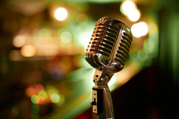 Close up on shiny chrome mic in vintage style against blurred lights in jazz club, copy space