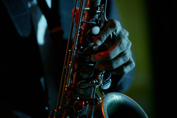 Close up on hand of professional saxophonist playing music during live performance in bar