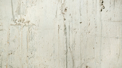 A close-up of a weathered concrete wall with a rough, textured surface. Rough bright concrete wall background.