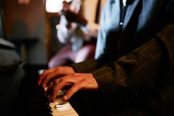 Close up on hands of professional male jazz musician playing music on piano during live performance...