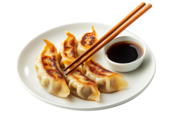 Grilled Japanese gyoza dumplings served on white plate with soy sauce and wooden chopsticks, isolated on white transparent background