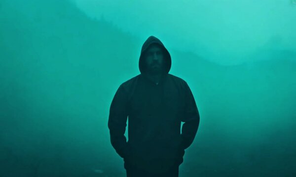 Zoom Pan of Mysterious Man in Hoodie with Teal Fog Background