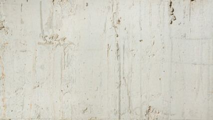 A close-up of a weathered concrete wall with a rough, textured surface. Rough bright concrete wall background.