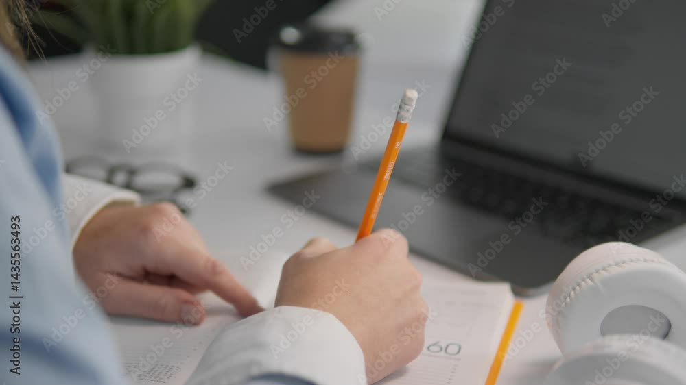 Poster in a focused study environment, a dedicated individual is taking notes with a pencil on paper. a lap