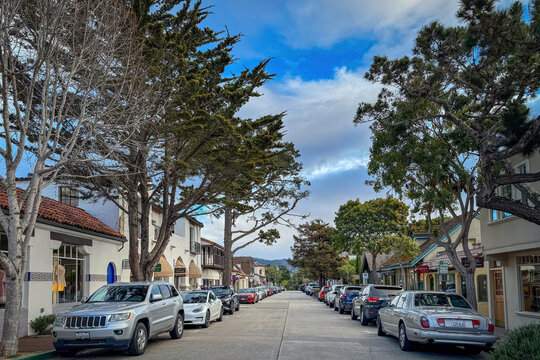 Carmel-by-the-Sea, California, USA - April 13, 2024: Dolores Street with parking cars against blue sky with clouds
