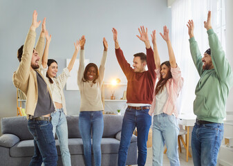 Obraz premium Happy friends, diverse students team at home, people showing support, active multinational cheerful best raised hands dancing spend time together moving in living room, enjoy life weekend having fun