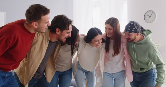 Group of happy multiracial friends, students or colleagues hugging each other and having fun. Cheerful diverse people laughing, enjoying time together and positive emotions. Friendship concept.