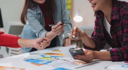 Web designers and mobile app developers are discussing wireframes and prototypes, collaborating on user interface and user experience design for a new mobile application