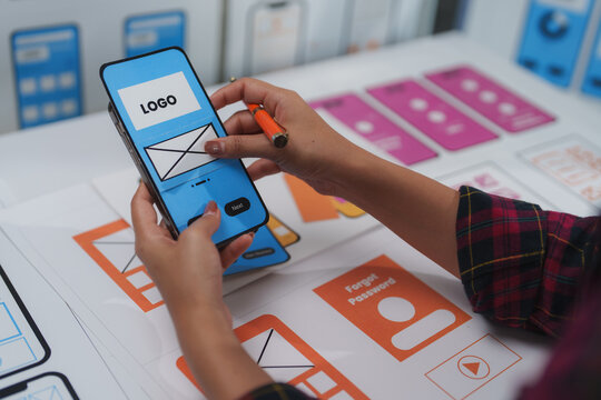 Ux designer working on a mobile application wireframe using a paper prototype of the user interface, testing user experience and functionality