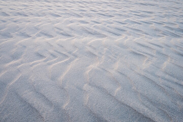 Smooth sand ripples creating a natural abstract texture, perfect as a serene, minimalistic background for creative designs