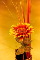 Rotgelbe Gerbera in Ziervase mit Dekoschmetterling