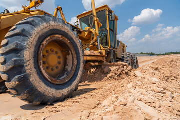 A robust yellow grader carves through the earth on a construction site, a testament to the power of...