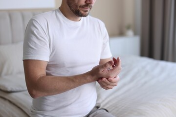Man suffering from pain in palm on bed at home, closeup