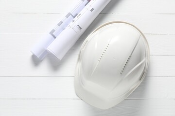 Different technical drawings and hard hat on white wooden table, flat lay