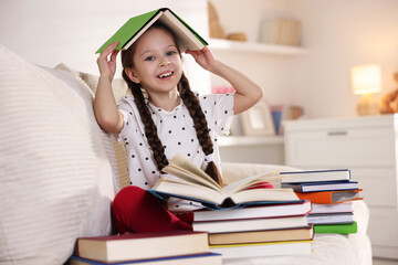 Cute girl with books on sofa at home