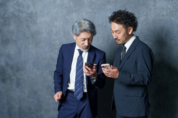 スマホを見て連絡先を交換するビジネスマンたち.