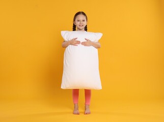 Cute girl with pillow on orange background