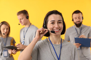 Technical support call center. Team of friendly operators on yellow background