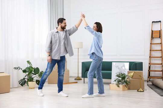 Moving day. Happy couple dancing in their new home