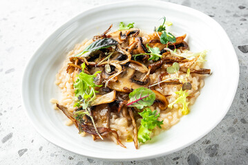 A creamy risotto topped with sautéed mushrooms and fresh greens, elegantly presented on a white plate, ideal for showcasing gourmet vegetarian cuisine and comforting meals.