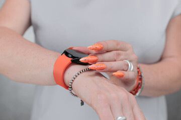Woman hand with long nails and light orange red neon manicure