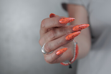 Woman hand with long nails and light orange red neon manicure