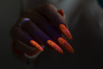 Woman hand with long nails and light orange neon manicure