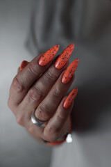 Woman hand with long nails and light orange neon manicure