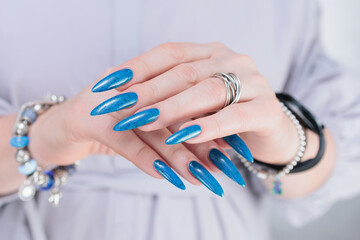 Woman's beautiful hand with long nails and bright blue manicure