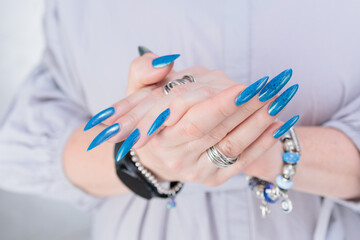 Woman's beautiful hand with long nails and bright blue manicure