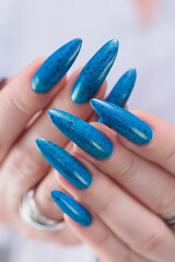 Woman's beautiful hand with long nails and bright blue manicure