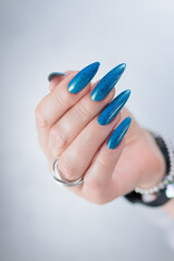 Woman's beautiful hand with long nails and bright blue manicure