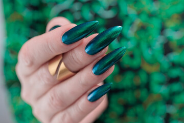 Woman's beautiful hand with long nails and blue and green nail polish