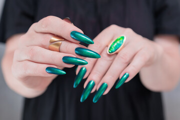 Woman's hand with long nails and green blue nail polish