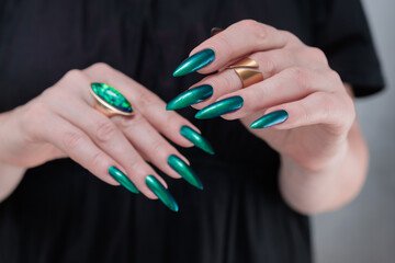 Woman's hand with long nails and green blue nail polish